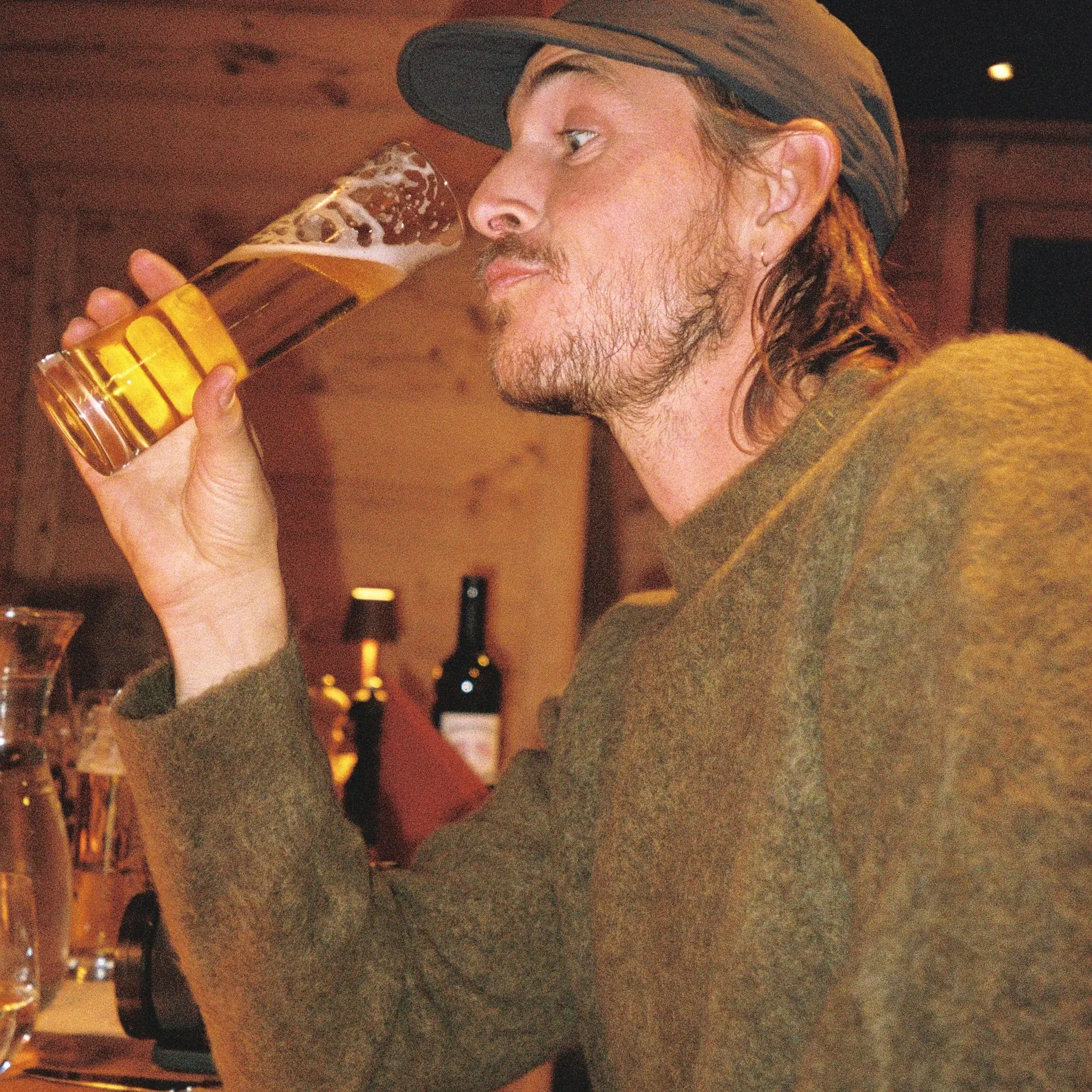An image of someone drinking a beer in a wool sweater